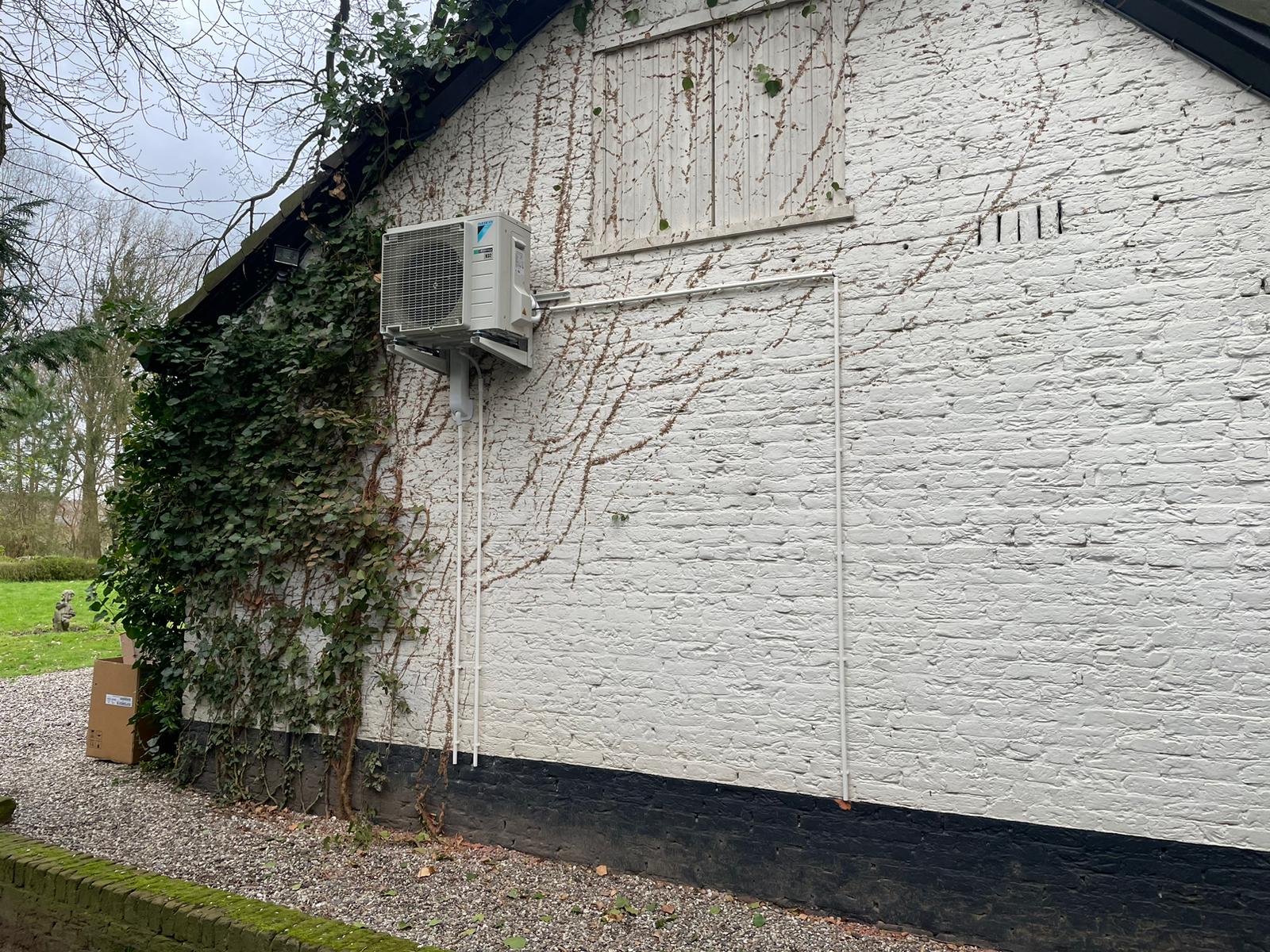 Buitenunit hoog aan een witte gevel