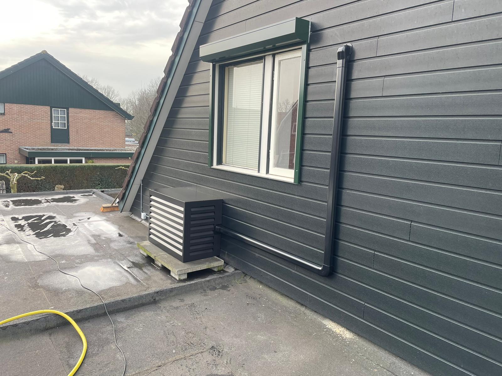 Omkasting op een plat dak naast een donkere houten gevel
