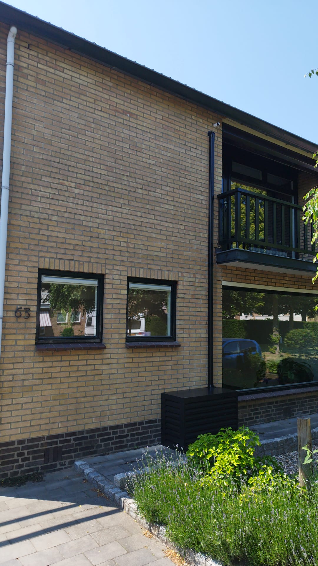 Zwarte airco-omkasting aan de voorgevel met zwarte leidinggoot