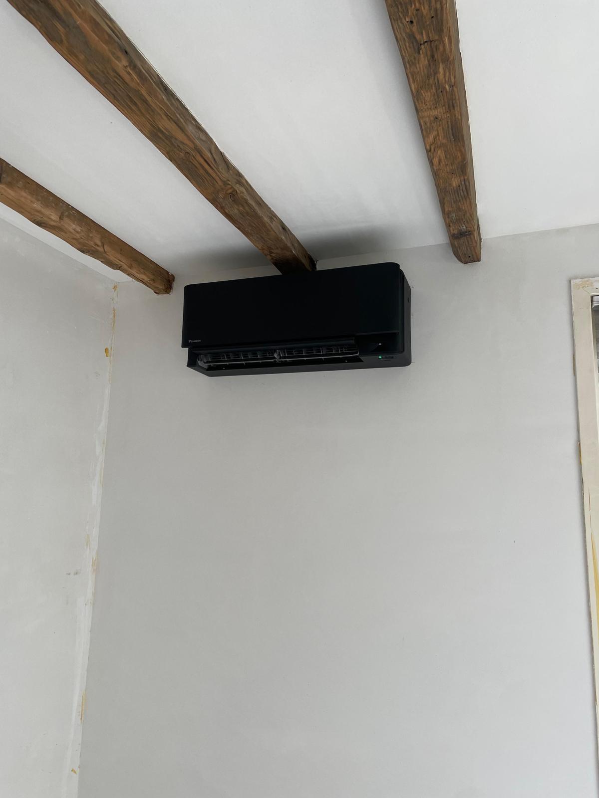 Zwarte binnenunit onder houten plafondbalken