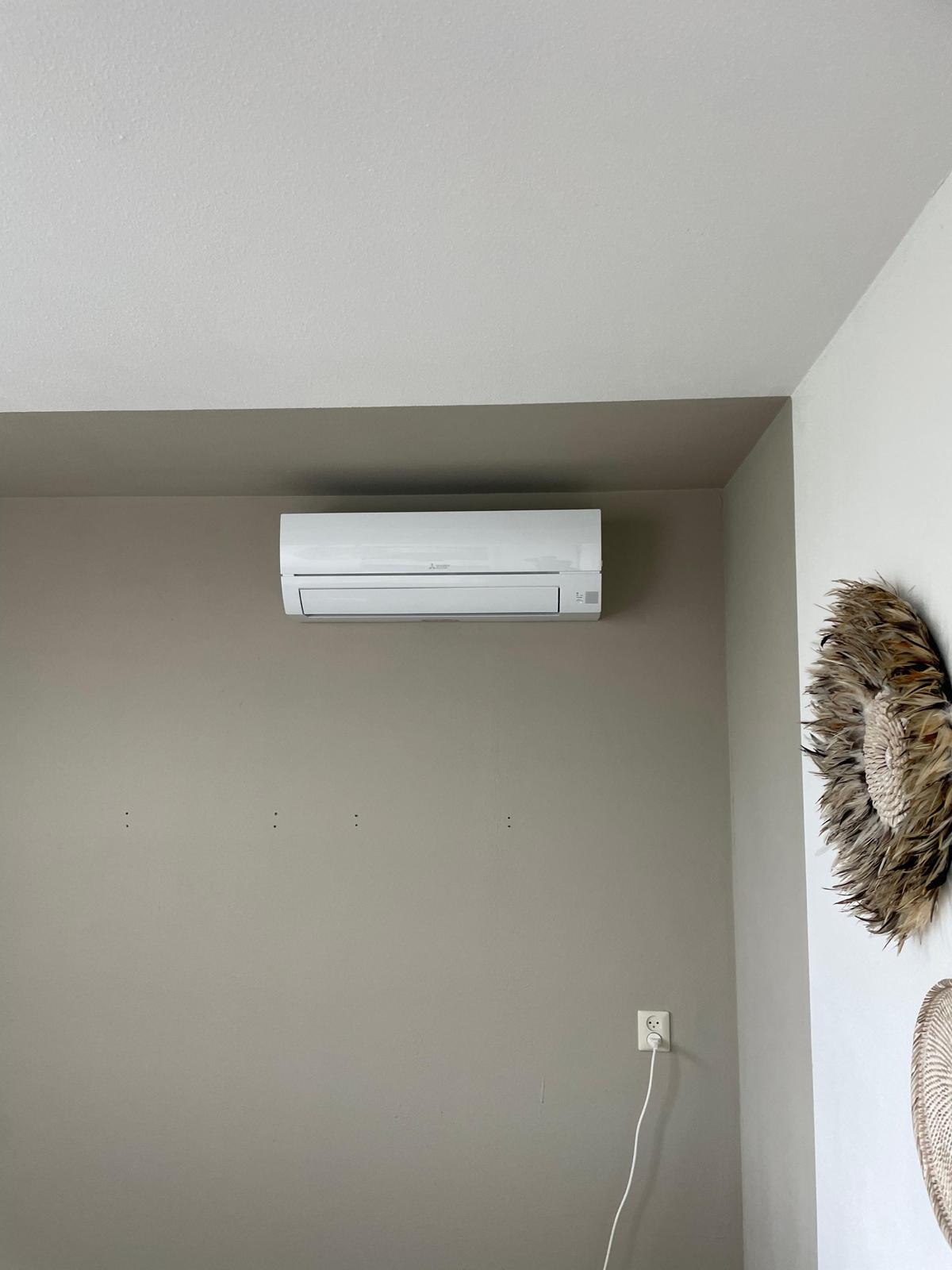 Witte binnenunit hoog aan de wand in een rustige kamer