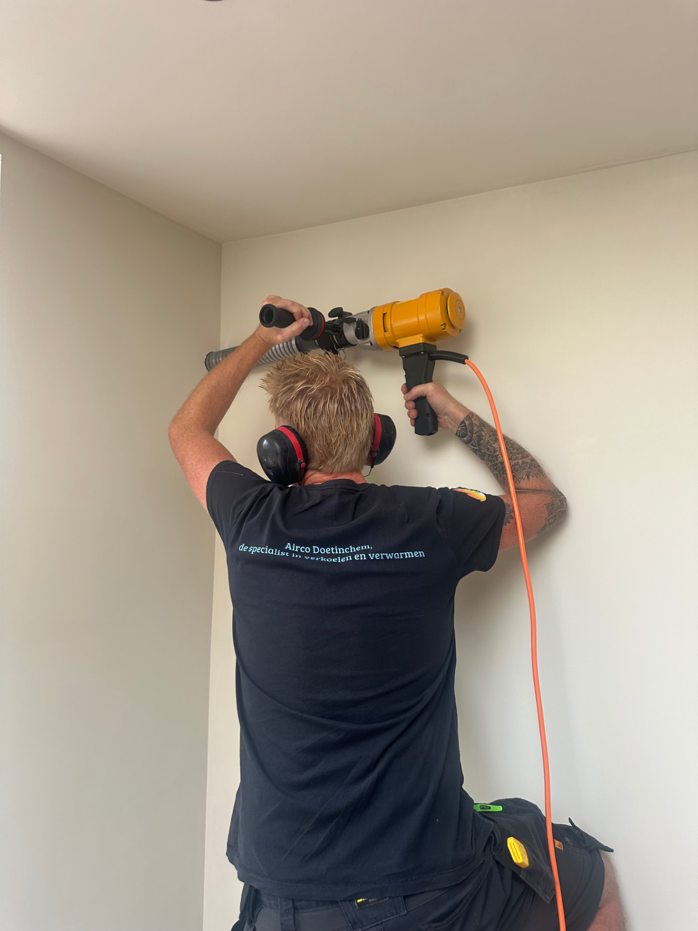 Monteur van Airco Doetinchem boort zorgvuldig een doorvoer voor de airco-installatie